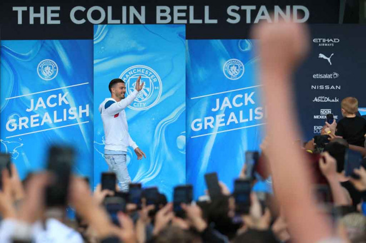 Jack Grealish melambaikan tangan kepada penggemar Manchester City di luar Stadion Etihad selama peresmiannya pada Senin, 9 Agustus 2021.