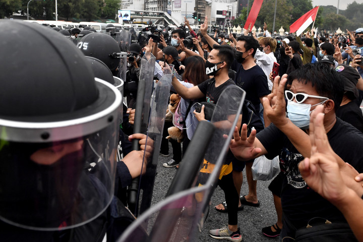 Pengunjuk rasa pro-demokrasi menghadapi polisi anti huru hara selama protes yang menyerukan pengunduran diri perdana menteri Prayut Chan-O-Cha atas penanganan pemerintah Thailand terhadap krisis virus korona dan mengubah undang-undang saat ini, di Bangkok pada 11 Agustus 2021.