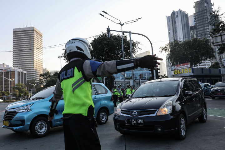 Petugas kepolisian mengalihkan kendaraan berplat nomor ganjil saat pelaksanaan pengendalian mobilitas ganjil genap terhadap kendaraan yang akan memasuki kawasan Jalan Sudirman, Jakarta, Kamis, 12 Agustus 2021.