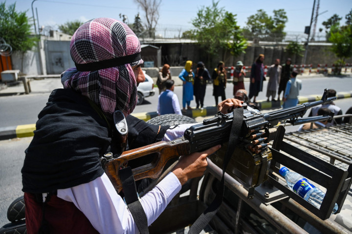 Seorang pasukan Taliban menggunakan senapan mesin di atas kendaraan saat mereka berpatroli di sepanjang jalan di Kabul pada 16 Agustus 2021.