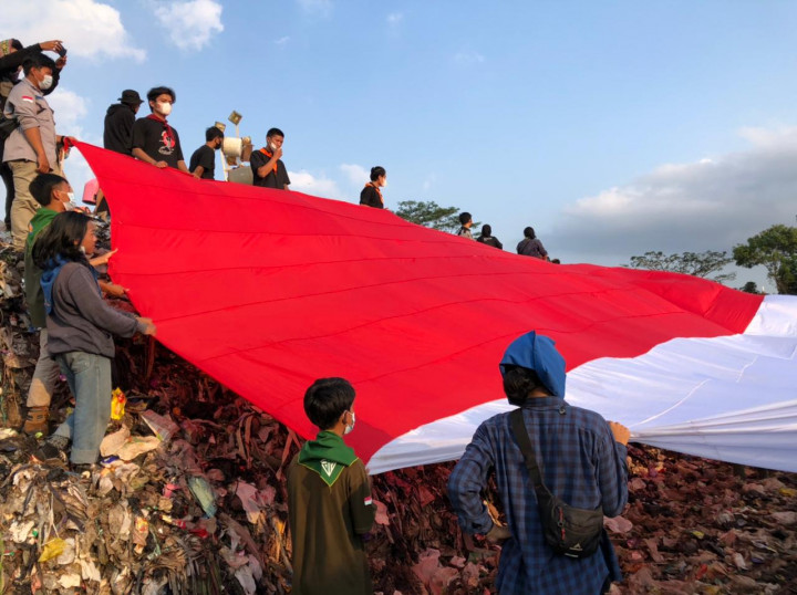 Para komunitas peduli lingkungan membentangkan bendera merah putih raksasa berukuran 70 x 60 meter di atas tumpukan sampah Tempat Pembuangan Akhir (TPA) Ciangir, Tamansari, Kota Tasikmalaya pada Minggu, 15 Agustus 2021.