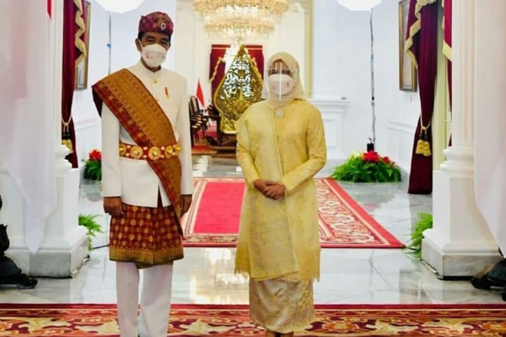Ibu Negara Iriana Joko Widodo tampak anggun mengenakan busana nasional berwarna gading dilengkapi kain songket. Penampilan sederhana Ibu Iriana tampak dilengkapi dengan jilbab berwarna senada.