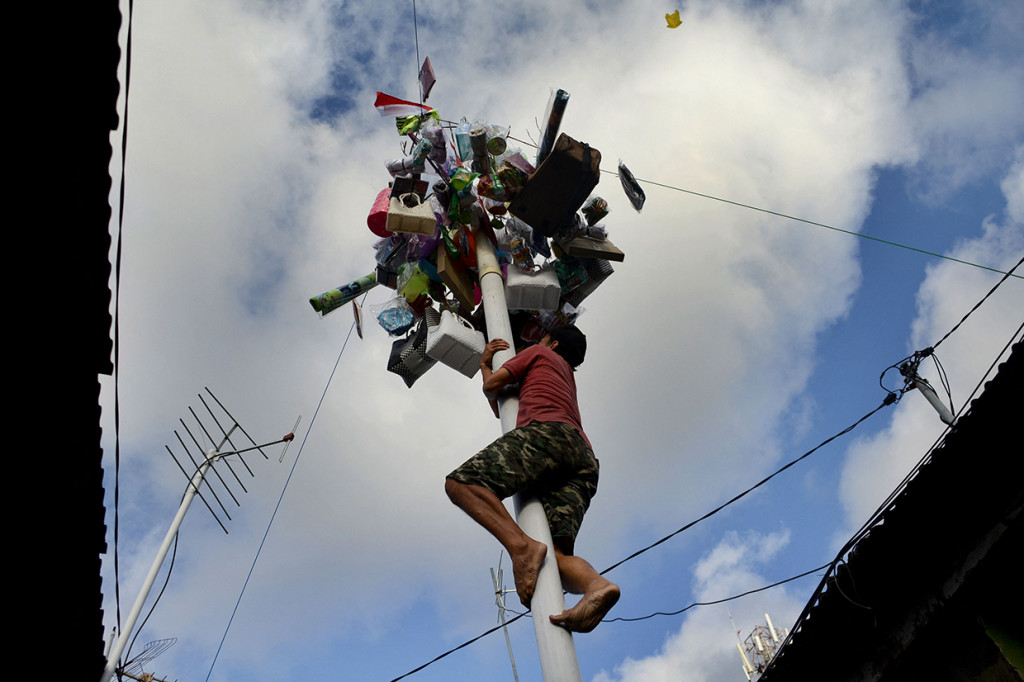 Warga mengikuti lomba panjat pinang saat perayaan Hari Kemerdekaan RI ke-76 di Bandung. AFP Photo/Sonny Tumbelaka