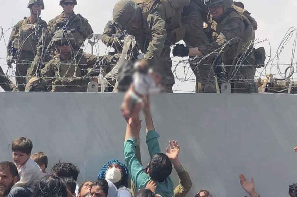 Sebuah video memilukan menunjukkan seorang Marinir AS mengangkat bayi di atas dinding kawat berduri di Bandara Kabul menarik perhatian global pada hari Jumat, 20 Agustus 2021, di tengah kekacauan ribuan orang yang mencoba melarikan diri dari Afghanistan yang baru dikendalikan oleh Taliban.