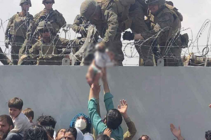 Sebuah video memilukan menunjukkan seorang Marinir AS mengangkat bayi di atas dinding kawat berduri di Bandara Kabul menarik perhatian global pada hari Jumat, 20 Agustus 2021, di tengah kekacauan ribuan orang yang mencoba melarikan diri dari Afghanistan yang baru dikendalikan oleh Taliban.