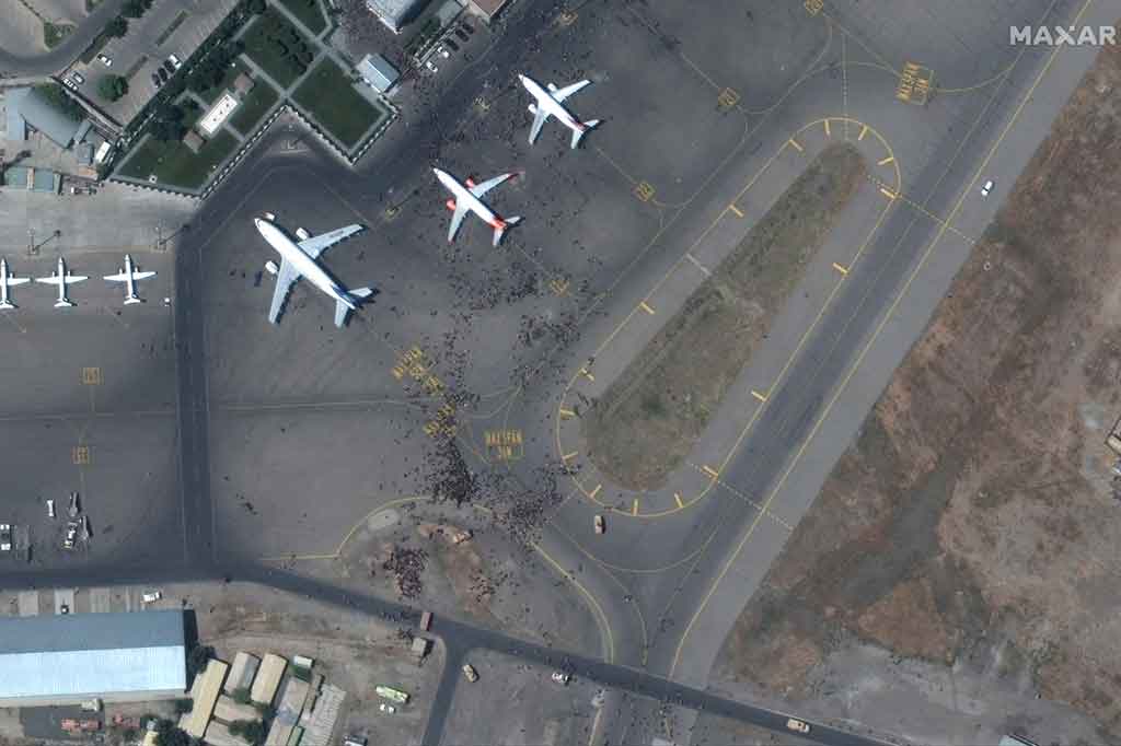 Kerumunan orang yang berupaya menyelamatkan diri dari Afghanistan memadati bandara Kabul sejak kelompok Taliban mengambil alih kekuasaan pada Minggu, 15 Agustus 2021. Banyak dari mereka terlihat mencoba menaiki pesawat saat akan lepas landas.