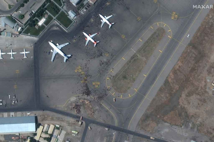 Kerumunan orang yang berupaya menyelamatkan diri dari Afghanistan memadati bandara Kabul sejak kelompok Taliban mengambil alih kekuasaan pada Minggu, 15 Agustus 2021. Banyak dari mereka terlihat mencoba menaiki pesawat saat akan lepas landas.