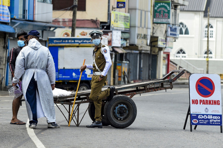 Aparat kepolisian memeriksa seorang warga yang tetap beraktivitas di luar rumah selama penerapan lockdown di Kolombo, Sri Lanka.