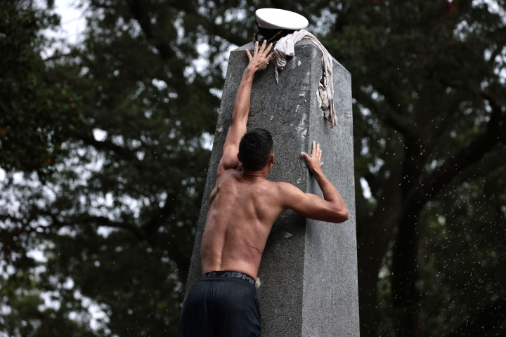Seorang siswa mencoba menempatkan topi kakak kelas selama pendakian Monumen Herndon taruna 2023 di Akademi Angkatan Laut AS, 22 Agustus 2021 di Annapolis, Maryland.