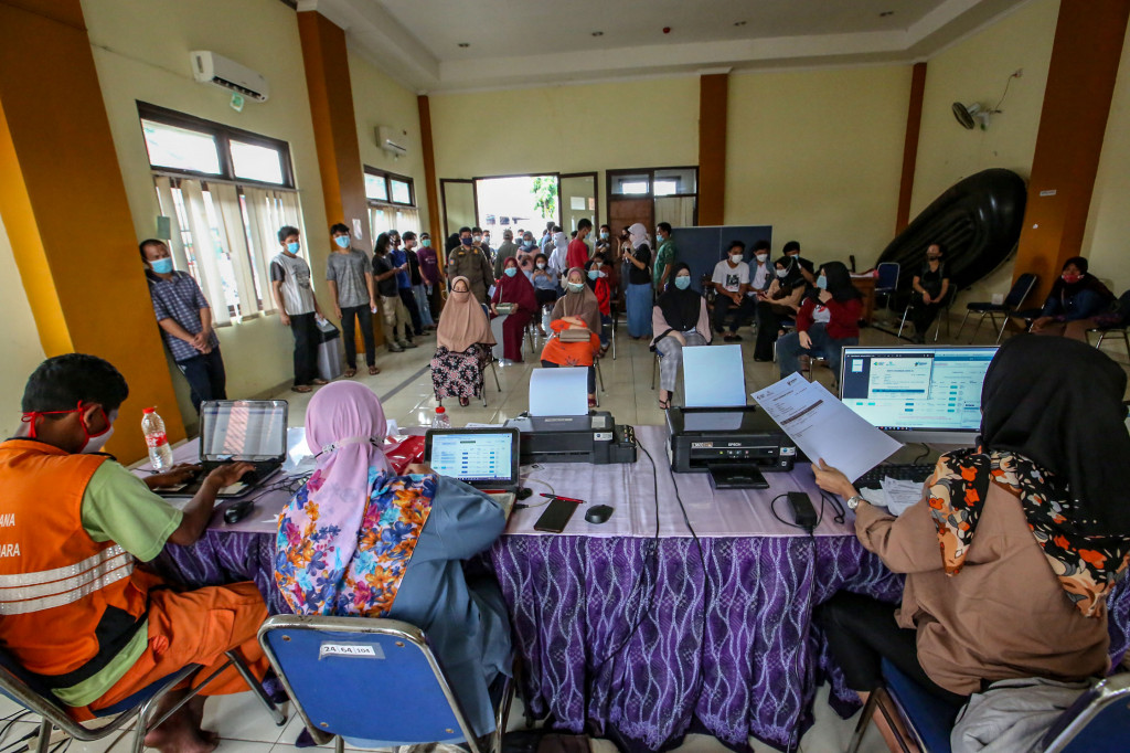 Warga mengantre untuk mengambil sertifikat vaksinasi covid-19 saat mobil vaksin keliling singgah di Gedung Balai Kesehatan RS Pondok, Cipinang Muara, Jakarta.