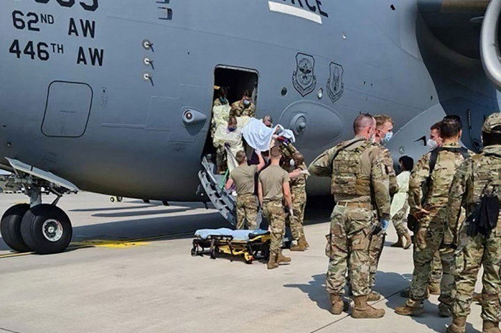 Tim medis mengevakuasi seorang perempuan Afghanistan dari pesawat Angkatan Udara AS C-17, dengan kode Reach 828, beberapa saat setelah melahirkan di atas pesawat, saat mendarat di Pangkalan Udara Ramstein, Jerman, Sabtu 21 Agustus 2021.