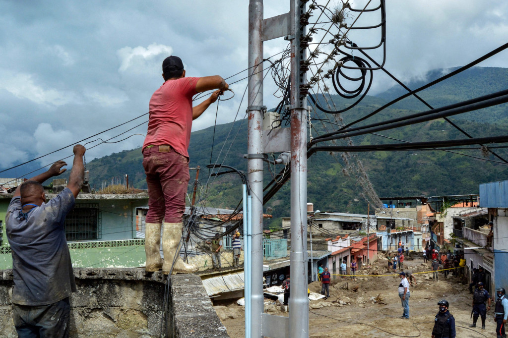 Warga mencoba memperbaiki kabel listrik di daerah di mana beberapa rumah hancur oleh tanah longsor yang disebabkan oleh hujan lebat di Tovar, negara bagian Merida, Venezuela.