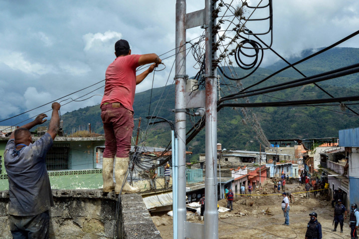 Warga mencoba memperbaiki kabel listrik di daerah di mana beberapa rumah hancur oleh tanah longsor yang disebabkan oleh hujan lebat di Tovar, negara bagian Merida, Venezuela.