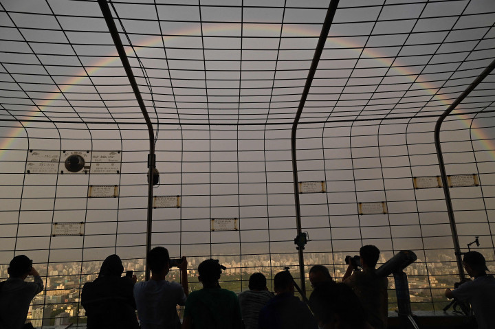 Sejumlah warga saat melihat pemandangan pelangi ganda terlihat dari Central Television Tower di Beijing, Tiongkok.