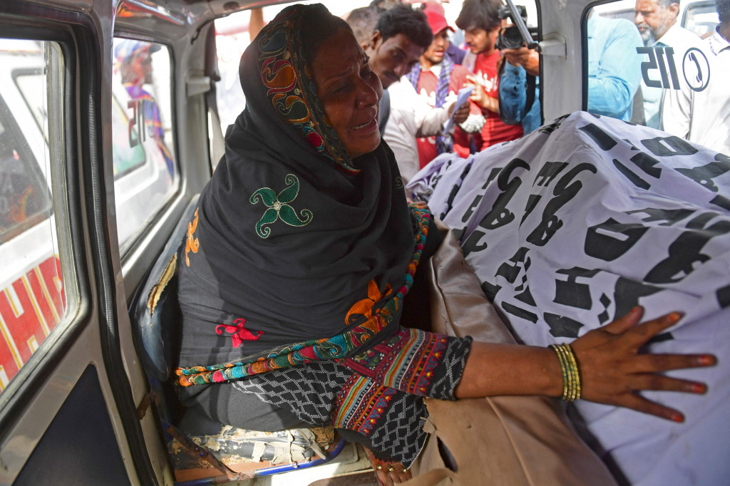 Seorang wanita berduka saat duduk di dalam ambulans di sebelah jenazah kerabatnya yang meninggal dalam kebakaran pabrik di Karachi pada 27 Agustus 2021.