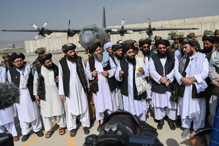 Para pemimpin Taliban berjalan masuk ke dalam bandara dengan dikawal pasukan khusus mereka.