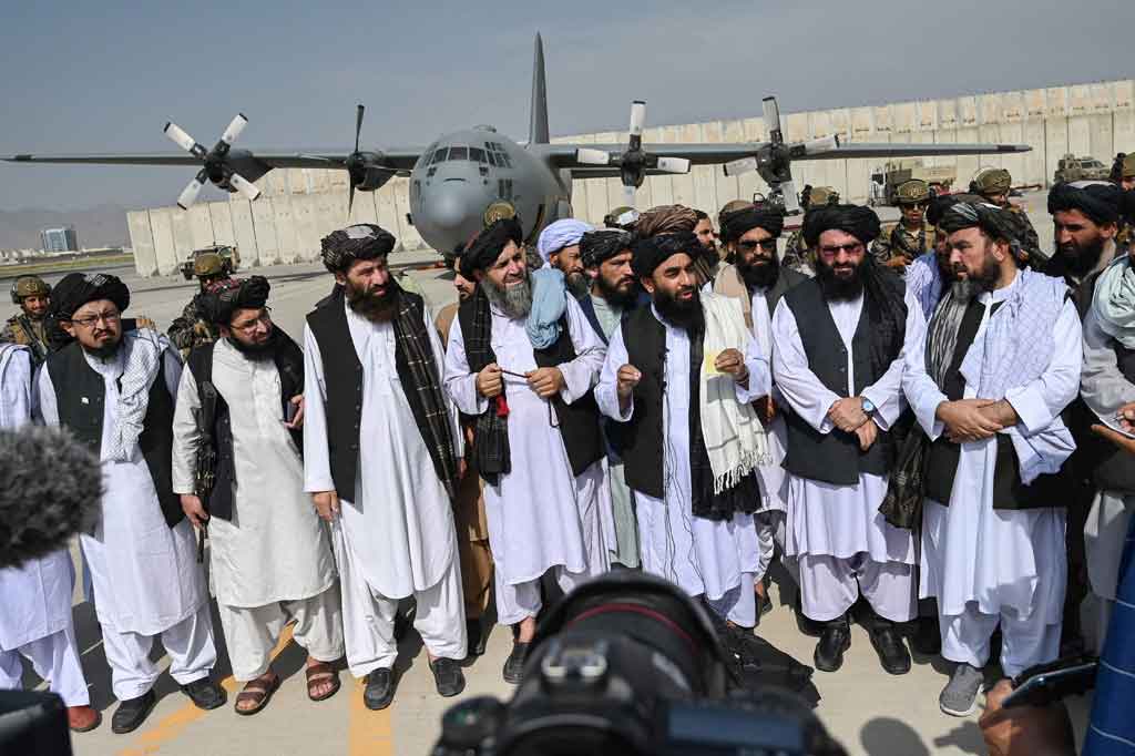 Beberapa jam setelah pasukan asing terakhir terbang keluar dari Afghanistan, para pemimpin Taliban berjalan dengan penuh kemenangan melalui bandara, diapit oleh pasukan khusus yang mengenakan peralatan tempur.