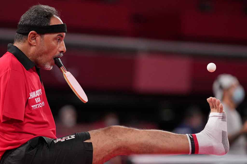 Saat melakukan servis, Hamadtou menjentikkan bola ke atas dengan kaki kanannya dan memukulnya dengan kuat dengan bet, yang dia pegang di antara giginya. Ini adalah teknik spektakuler yang tampaknya dia sempurnakan.