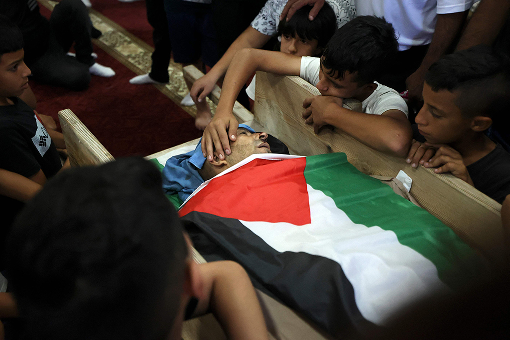 Yousef Jadallah, meletakkan tangannya di tubuh ayahnya Raed Jadallah, yang dibunuh oleh pasukan Israel di pintu masuk barat desanya saat kembali dari kerja, selama pemakamannya di Desa Beit, Tepi Barat Ur al-Tahta, Rabu, 1 September 2021.