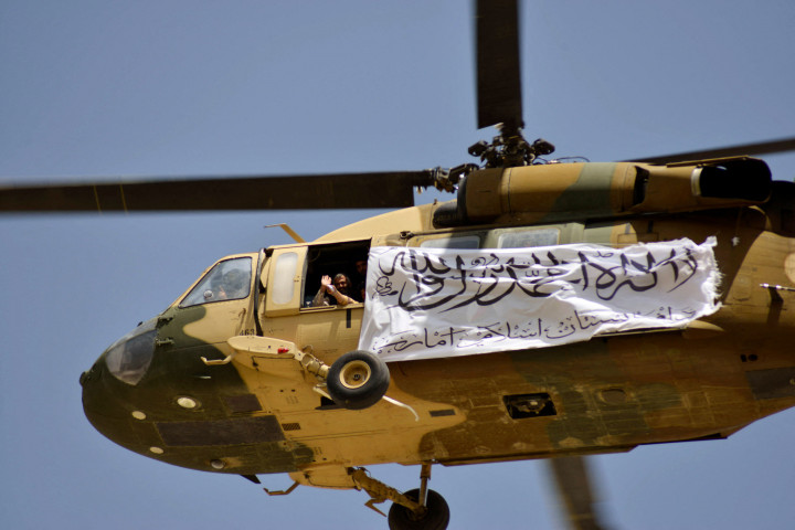 Dilansir AFP, Kamis, 2 September 2021, sebuah helikopter Black Hawk terbang berputar-putar di langit kota Kandahar, Afghanistan bagian selatan, pada Rabu, 1 September 2021, waktu setempat. Para petempur Taliban di bawahnya duduk dan berdiri di atas kendaraan militer Humvee yang dijarah dari AS.