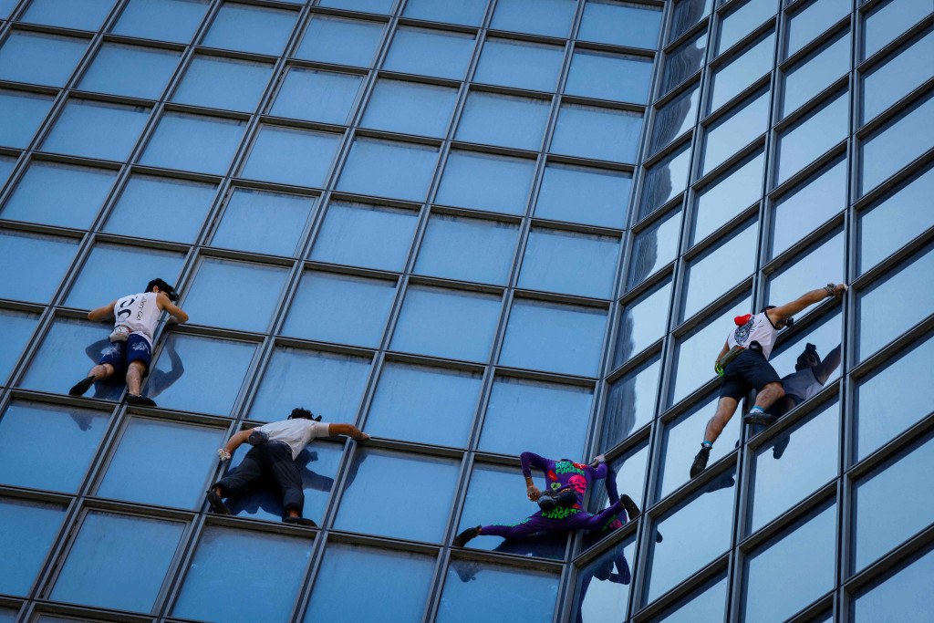 Pendaki Alain Robert (kedua kanan) atau Spiderman Prancis bersama Marcin Banot, Alexis Landot, dan Leo Urban memanjat Menara Total di La Defense, Paris, Prancis, Selasa, 7 September 2021.
