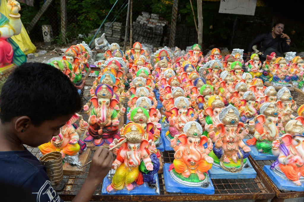 Seorang anak melukis patung Dewa Ganesha yang dipajang untuk dijual di kios pinggir jalan di Hyderabad, India, Kamis, 9 September 2021.