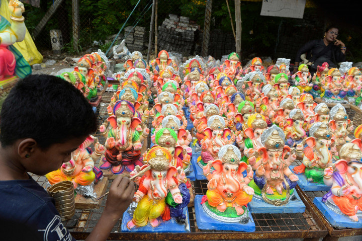 Seorang anak melukis patung Dewa Ganesha yang dipajang untuk dijual di kios pinggir jalan di Hyderabad, India, Kamis, 9 September 2021.