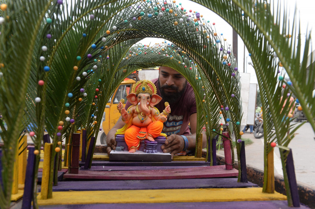 Seorang perajin memajang patung Dewa Ganesha untuk dijual di kios pinggir jalan di Hyderabad, India, Kamis, 9 September 2021.