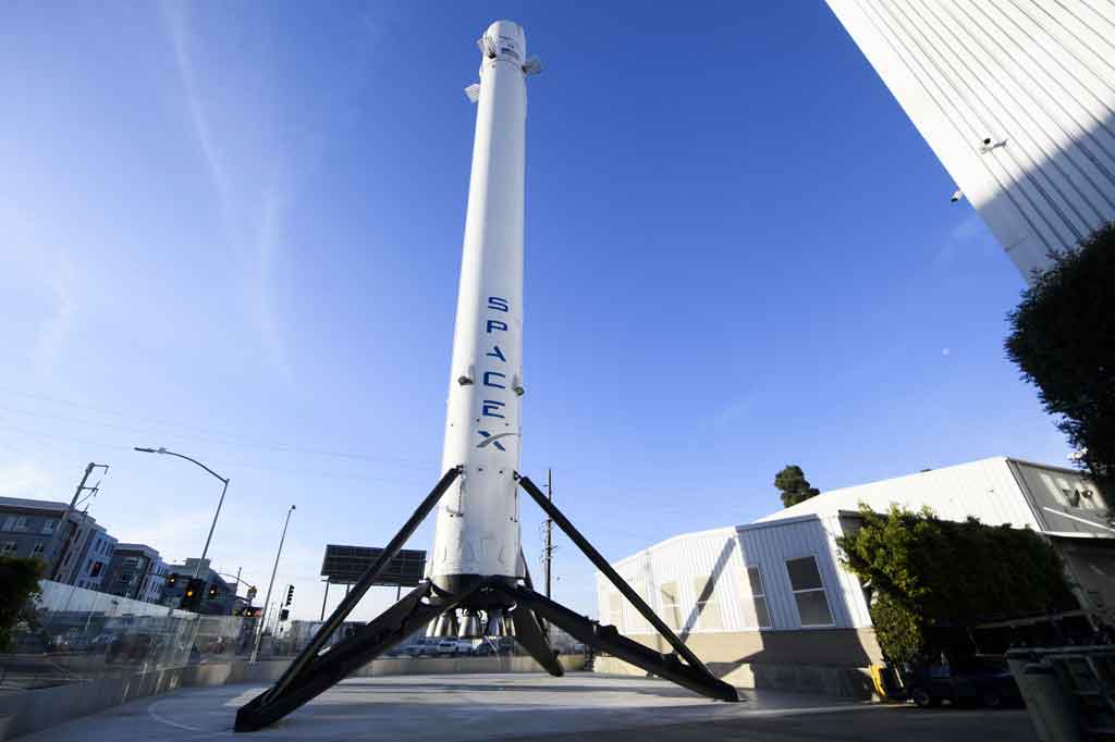 Di belakangnya menjulang roket raksasa Falcon 9, yang akan membawa empat anggota, semua awak sipil untuk misi tersebut, yang dijuluki Inspiration4.
