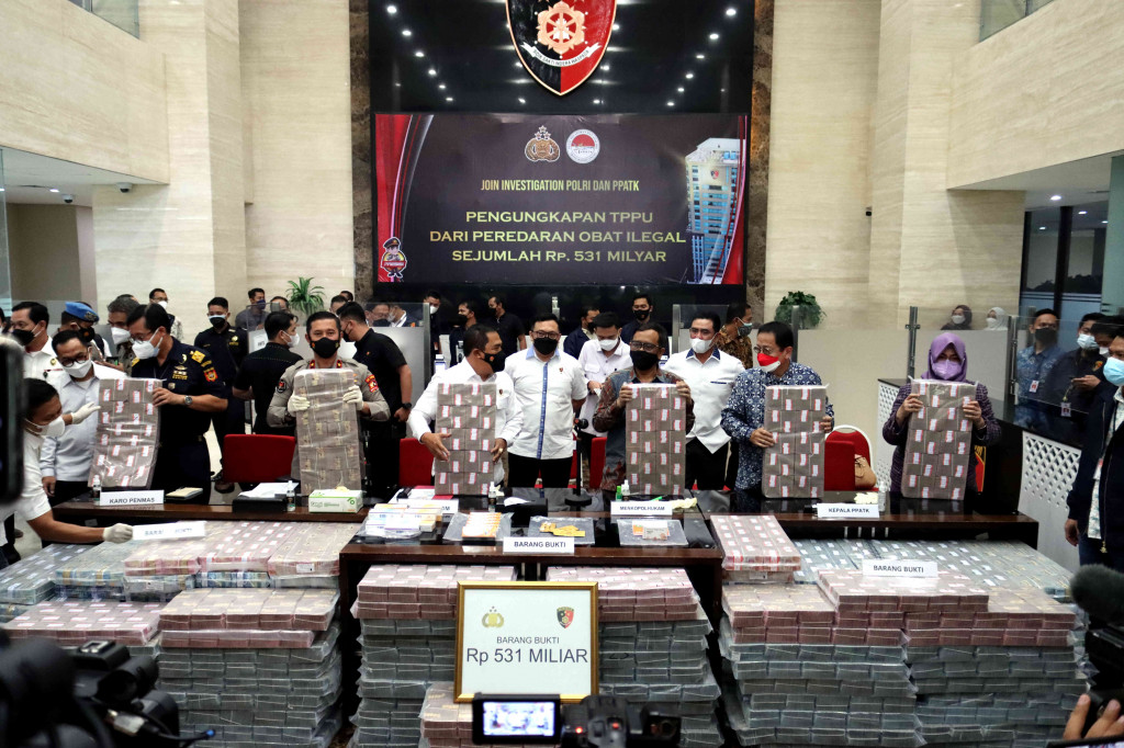 Kabareskrim Polri Komjen Agus Andrianto (keempat kiri) bersama Menkopolhukam Mahfud MD (ketiga kanan) memegang uang barang bukti saat konpers di Mabes Polri, Jakarta. Agus menjelaskan satu orang berinisial DP ditetapkan menjadi tersangka dalam kasus ini. Menurut Agus, DP sebenarnya tidak mempunyai keahlian dalam bidang farmasi.