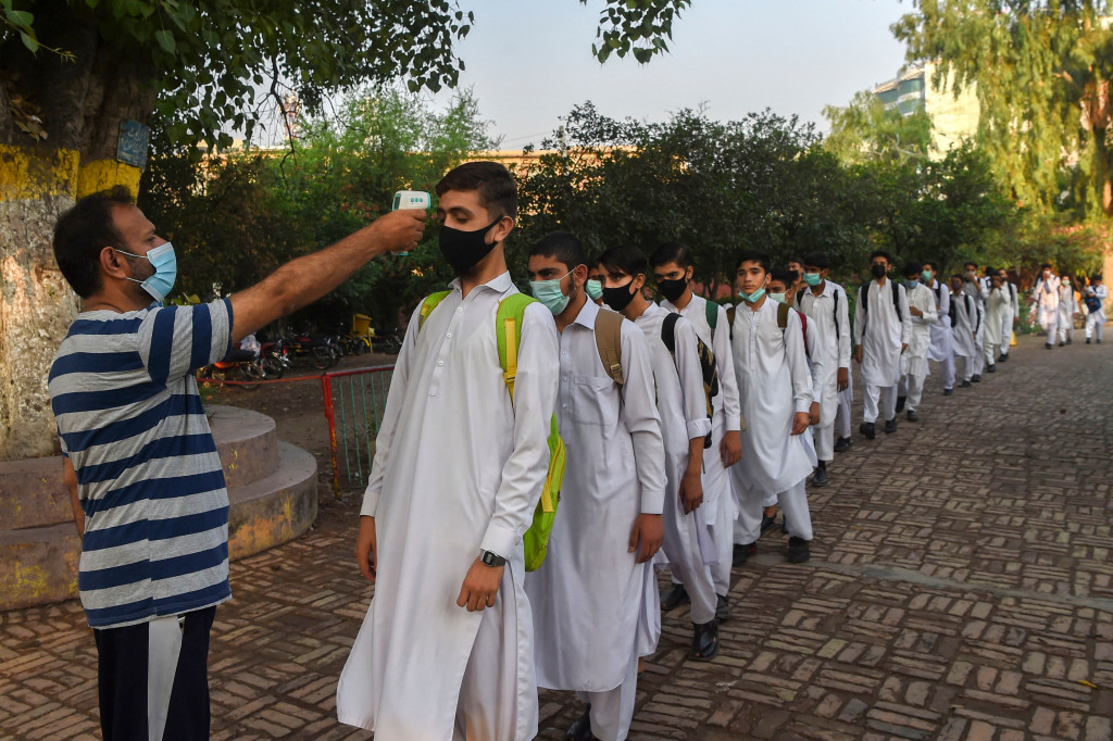 Seorang guru memeriksa suhu tubuh para siswa saat tiba di sebuah sekolah di Peshawar pada 16 September 2021.