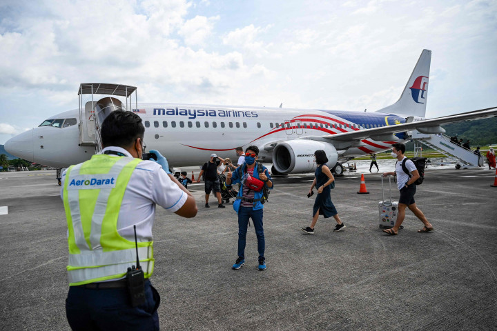 Petugas (kiri) membantu memotret penumpang setelah turun dari pesawat Boeing 738 Malaysia Airlines saat mendarat di Langkawi dari Bandara Internasional Kuala Lumpur, Kamis, 16 September 2021.