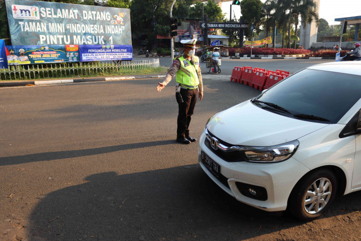 Petugas Satlantas Polres Metro Jakarta Timur memberikan imbauan kepada pengendara saat pengendalian mobilitas ganjil genap untuk pengunjung TMII di Jalan Pintu 1 TMII, Jakarta Timur, Sabtu, 18 September 2021.