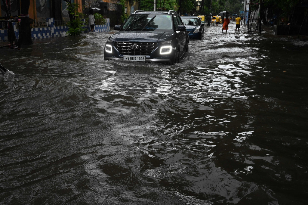 Sejumlah mobil melewati jalan yang tergenang air di tengah hujan lebat di Kolkata.