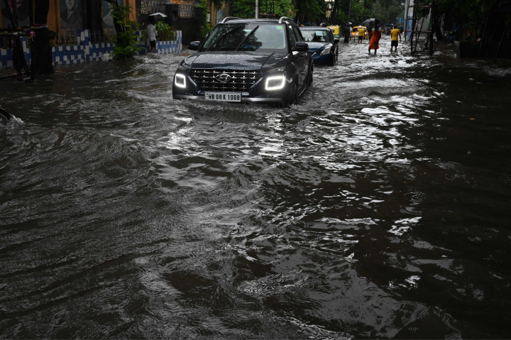 Sejumlah mobil melewati jalan yang tergenang air di tengah hujan lebat di Kolkata.