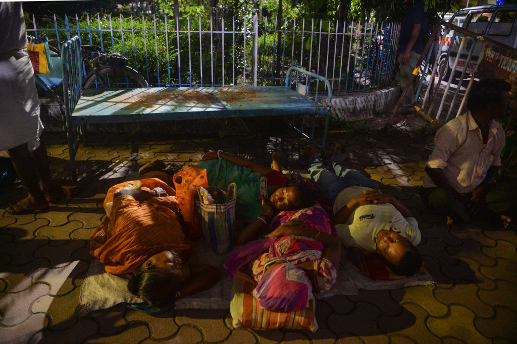 Sejumlah warga tertidur ketika mengantre untuk mendapatkan suntikan vaksin Covid-19 di sebuah rumah sakit pemerintah di Siliguri, India, Senin, 20 September 2021, malam.