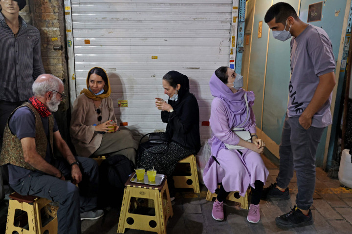 Pemilik Kazem Mabhutian (kiri), 63, minum teh dengan pelanggannya di luar kedai teh terkecil dan tertuanya yang terletak di gang Grand Bazaar di ibukota Iran, Teheran pada 20 September 2021.