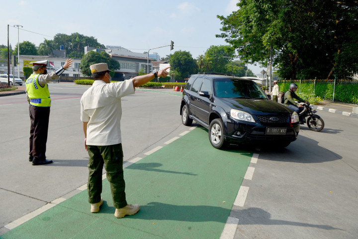 Petugas menghalau kendaraan dengan plat nomor ganjil yang menuju kawasan Jalan Sudirman di Jakarta, Minggu, 26 September 2021.