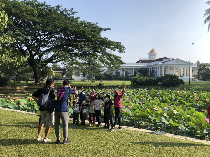 Warga berfoto dengan latar Istana Bogor saat berwisata ke Kebun Raya Bogor, Jawa Barat, Minggu, 26 September 2021. 
