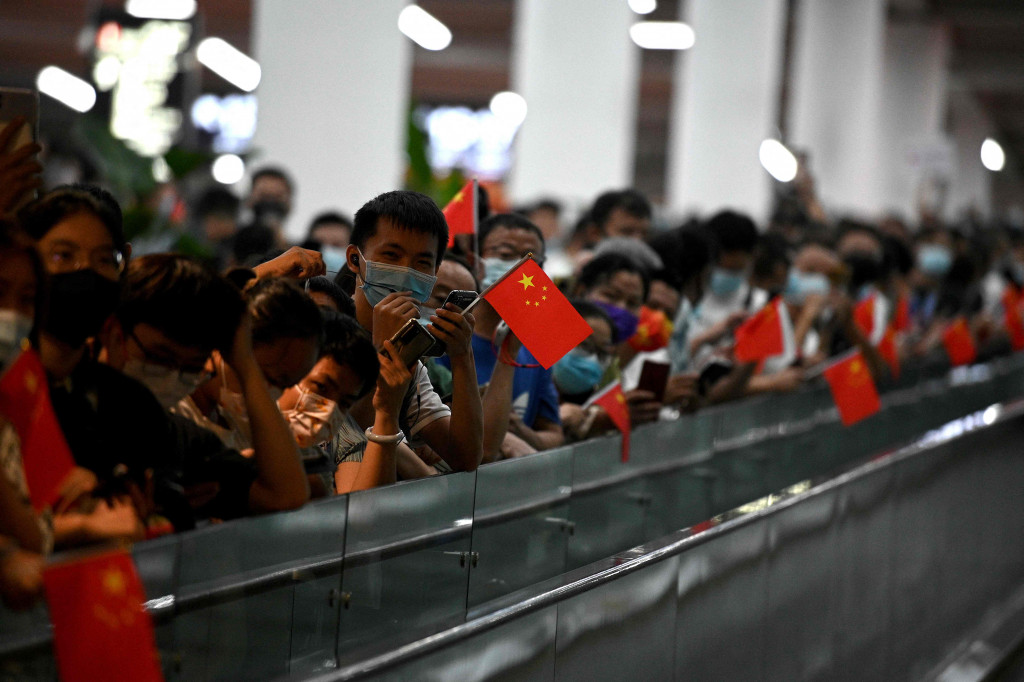 Meng mendarat di Shenzhen, Tiongkok, dan disambut banyak orang yang berteriak,