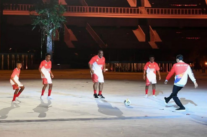 Presiden Joko Widodo menujukkan aksinya bermain bola di tengah pembukaan PON XX Papua, Sabtu, 2 Oktober 2021, malam.  Di tengah acara, seorang anak kecil berasal dari Papua mengajak Presiden turun ke lapangan untuk bermain bola dengan legenda sepak bola Indonesia Jack Komboy dan tiga anak muda Papua.