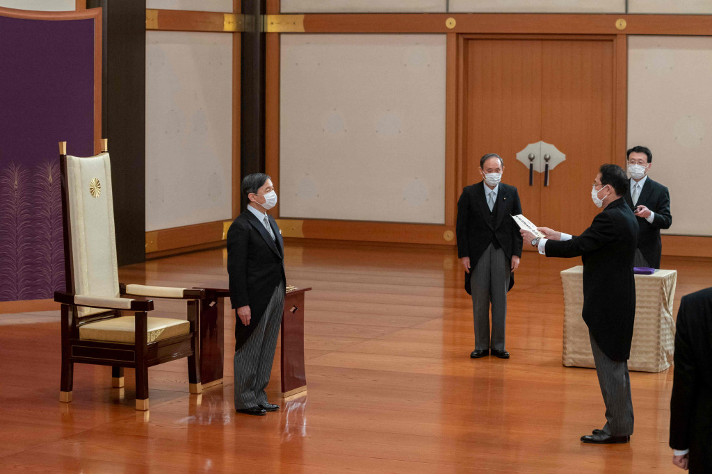 Kaisar Jepang Naruhito (kiri) berdiri di hadapan Perdana Menteri baru Fumio Kishida, dan mantan perdana menteri Yoshihide Suga (kedua dari kiri), selama upacara pengesahan Kishida di Istana Kekaisaran di Tokyo.
