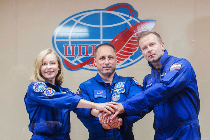 Kosmonaut Rusia Anton Shkaplerov (tengah) bersama aktris Yulia Peresild (kiri) dan sutradara film Klim Shipenko, saling berjabat tangan selama konferensi pers jelang ekspedisi ke Stasiun Luar Angkasa Internasional (ISS) di Baikonur Cosmodrome, Kazakhstan, Senin, 4 Oktober 2021. 