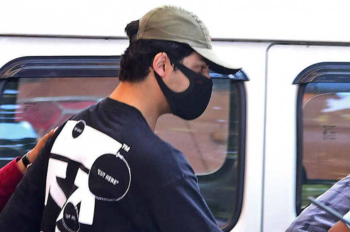 Putra aktor Bollywood Shah Rukh Khan, Aryan Khan, dikawal petugas penegak hukum di luar kantor Narcotics Control Bureau (NCB) untuk diinterogasi bersama dengan beberapa orang lainnya menyusul penggerebekan di sebuah pesta di kapal pesiar, di Mumbai pada Minggu, 3 Oktober, 2021.