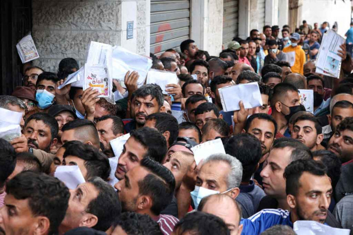 Di Jabalia, sebuah kamp pengungsi di Gaza utara, kerumunan pria yang memegang dokumen identitas mereka berbaris berharap mendapatkan izin untuk bekerja di Israel.