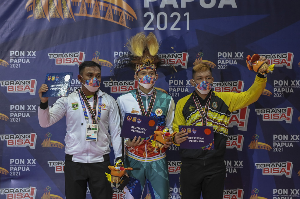 Pegulat putra Papua Reyna Fadli (tengah) bersama pegulat putra Sumbar Husnul Amri (kiri) dan pegulat putra Kalsel M. Fazrin (kanan) memperlihatkan medalinya saat penyerahan medali Gulat Putra Gaya Bebas kelas 97 Kg Putra PON Papua di Gor Futsal Dispora, Kabupaten Merauke, Papua.