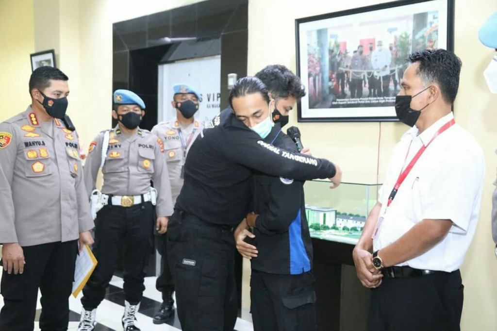 Anggota Polresta Tangerang Brigadir NP memeluk Fariz, mahasiswa yang dibantingnya saat unjuk rasa di komplek Pusat Pemerintahan Kabupaten Tangerang, Rabu, 13 Oktober 2021.