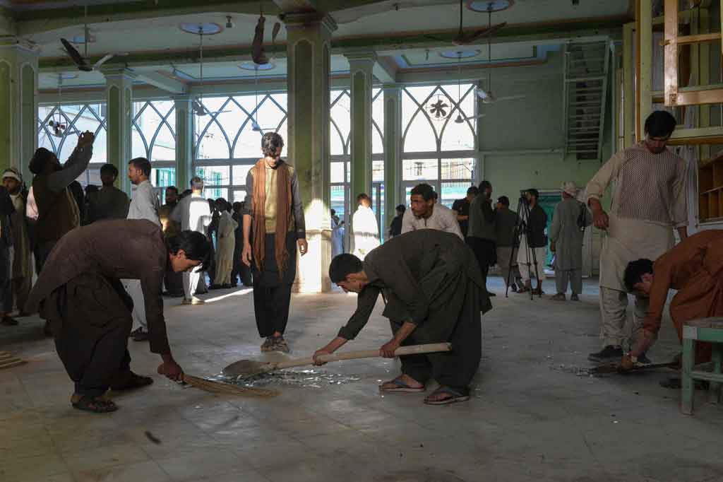 Warga mengumpulkan serpihan kaca di dalam sebuah masjid Syiah di Kandahar, pascaserangan bom bunuh diri saat salat Jumat, 15 Oktober 2021.