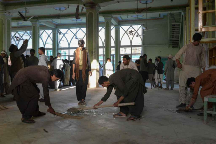 Warga mengumpulkan serpihan kaca di dalam sebuah masjid Syiah di Kandahar, pascaserangan bom bunuh diri saat salat Jumat, 15 Oktober 2021.