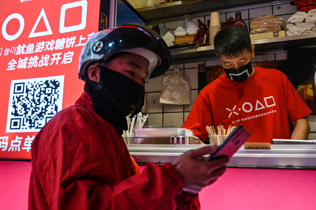 Pengantar makanan menunggu di toko kecil untuk dalgona, permen gula renyah yang ditampilkan dalam serial Netflix, Squid Game, di Shanghai, pada 12 Oktober 2021.